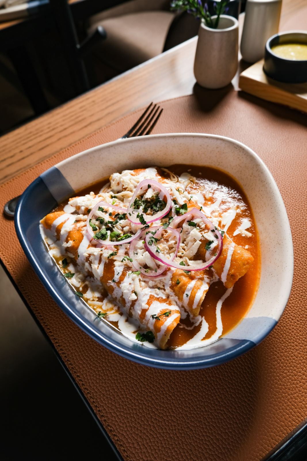 Enchiladas rojas con crema, queso y cebolla morada