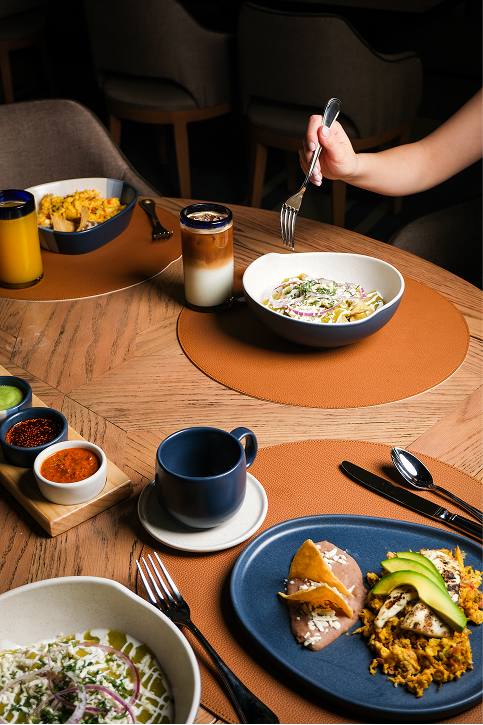 Mesa con chilaquiles, salsas y jugo